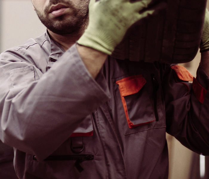 Motor trader carrying a tyre in a small garage